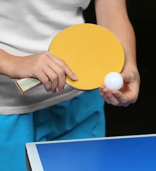hand holding a table tennis racket and ball
